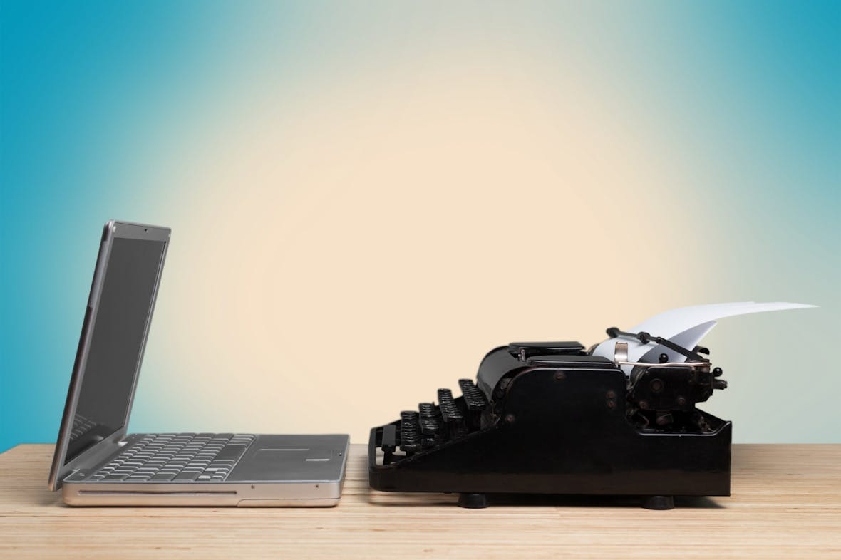Laptop og gammel skrivemaskin står ved siden av hverandre