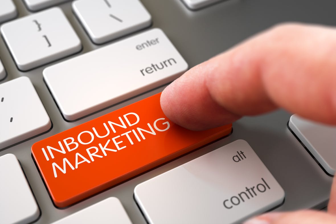 Finger trykker på et tastatur på en oransje knapp hvor det står "Inbound marketing"