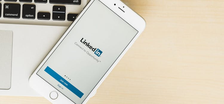 Smarttelefon med LinkedIn-appen åpen ligger på en laptop