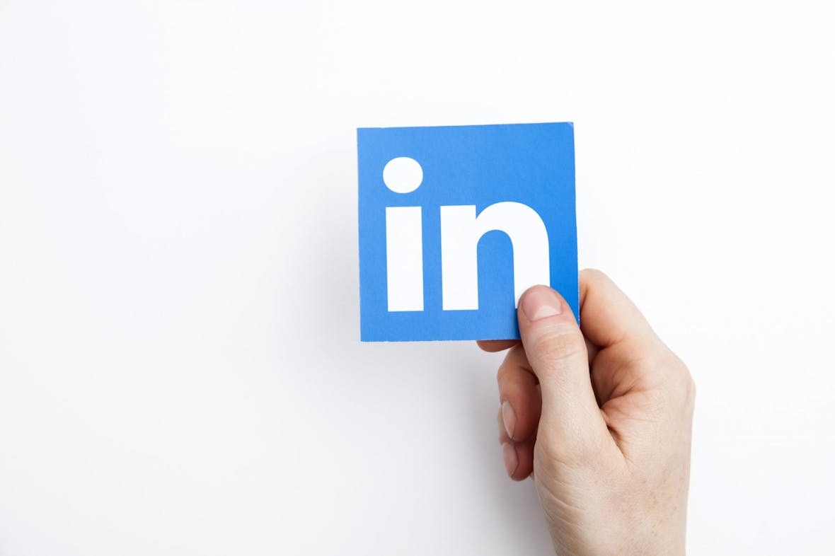 Hånd holder papir med linkedin-logoen