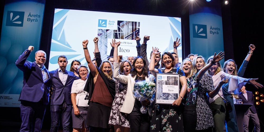 Iteos ansatte står på scenen og jubler over å ha vunnet prisen for Årets PR Byrå