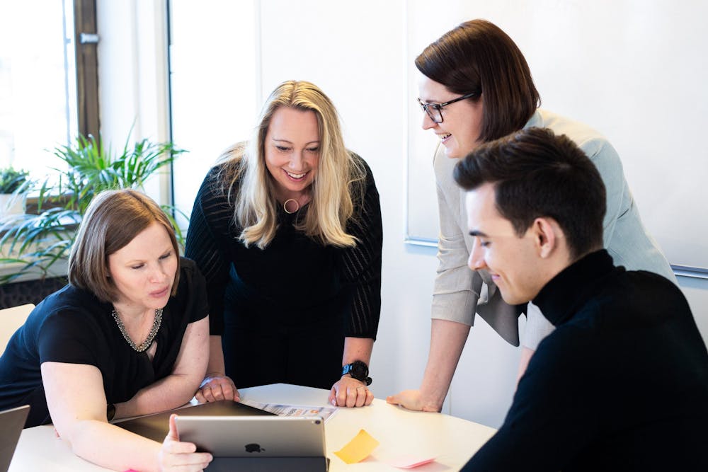 Fire kollegaer ser på iPad i arbeidsmøte