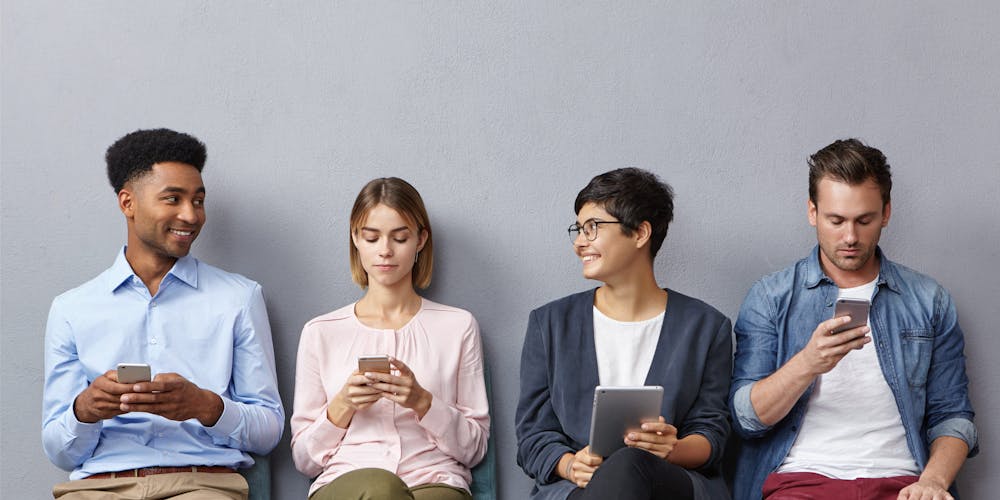 Foto av fire personer som sitter ved siden av hverandre med hver sin smarttelefon.