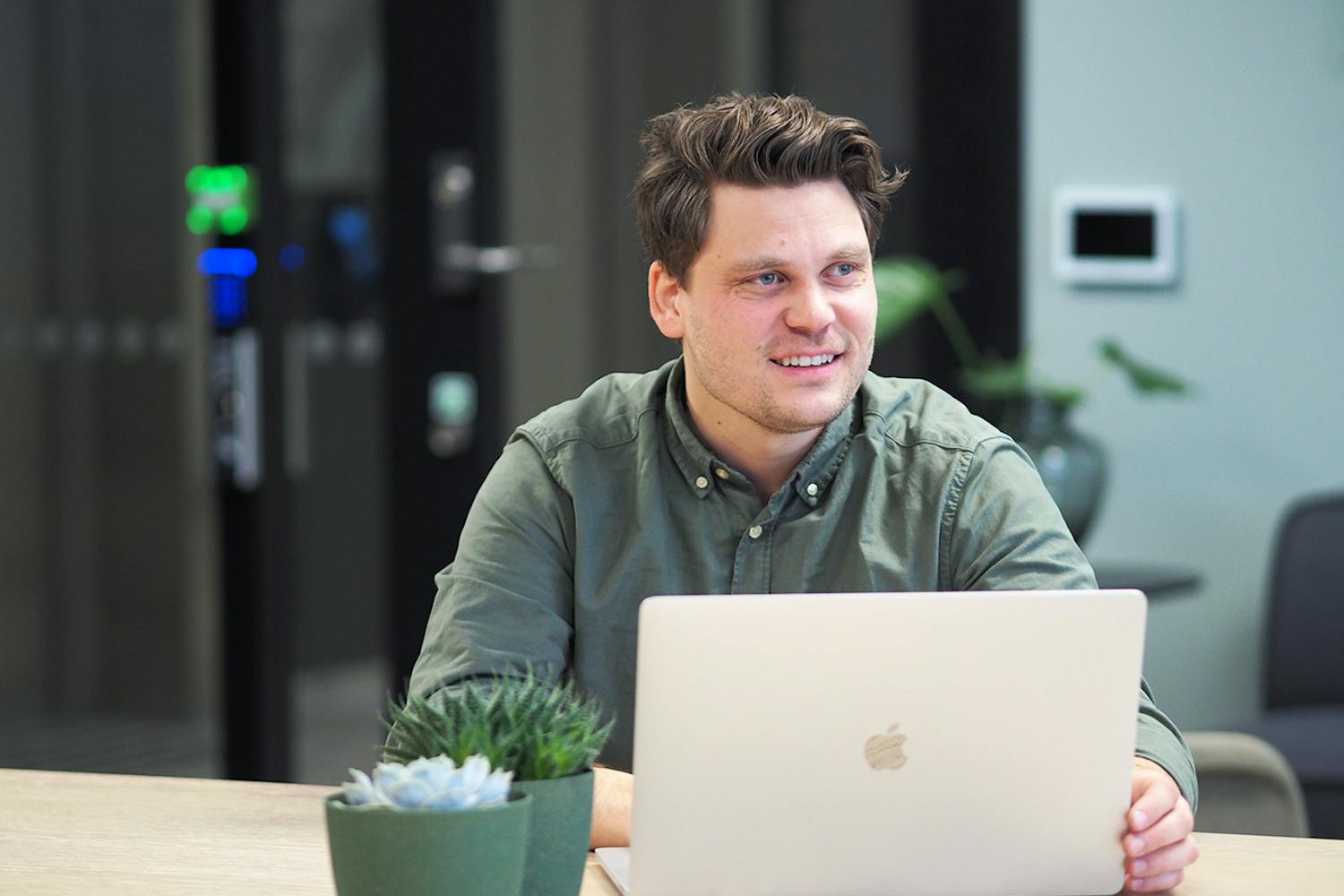 Hans-Petter som sitter på en Mac og smiler, for å illustrere markedsføringstrender i 2023.