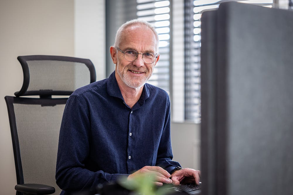 Morten Kristiansen, fagleder for innhold og PR i Iteo, foran dataskjermen, smiler til kamera.