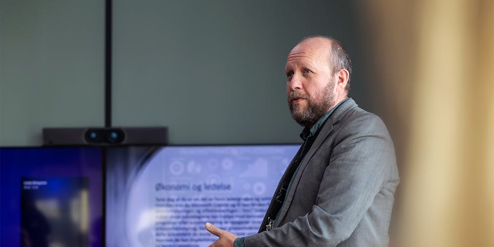 Hans-Henrik Torgersen foran en skjerm, mens han snakker om kunstig intelligens.
