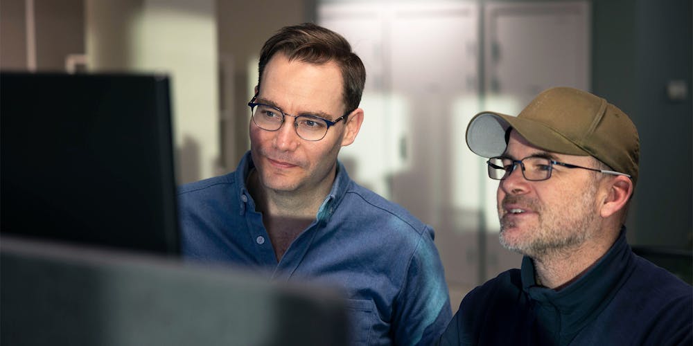 Stein Arne Gausen og SImen Berg ser positive resultater på en dataskjerm og smiler smått, når de bruker Min merkevaremåler for en kunde.