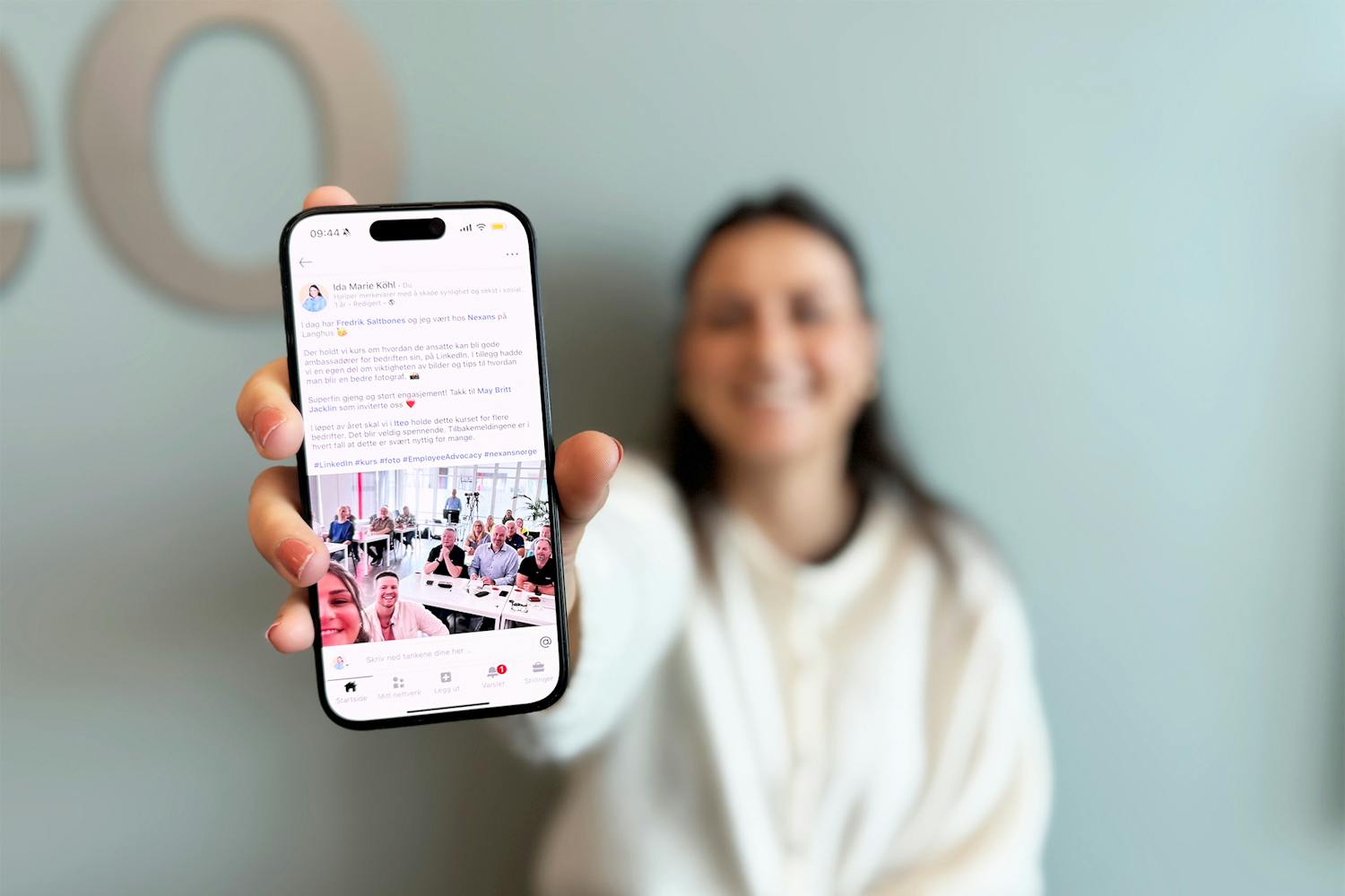 Ida Marie Köhl med mobilen i hånda og organisk LinkedIn-innlegg på skjermen.
