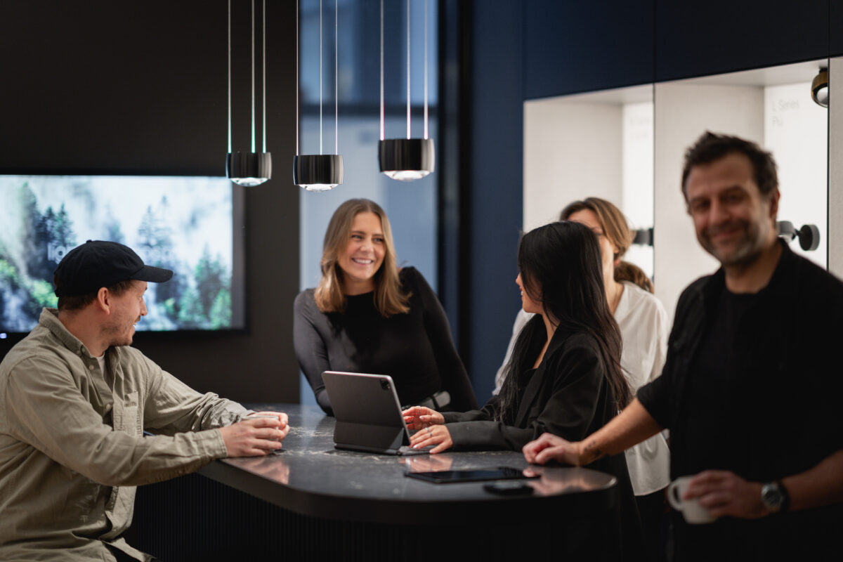 Elizabeth står og prater med kollegaer ved et bord